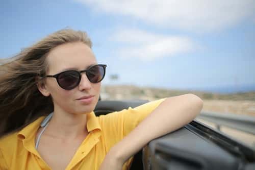 Woman in Yellow Polo Shirt Riding a Luxury Car