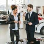 Man in Business Suit Discussing with Woman in Black Blazer around a car