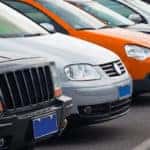 Cars of multiple makes and models parked in a row outside