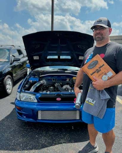 Man in front of blue car with the hood open