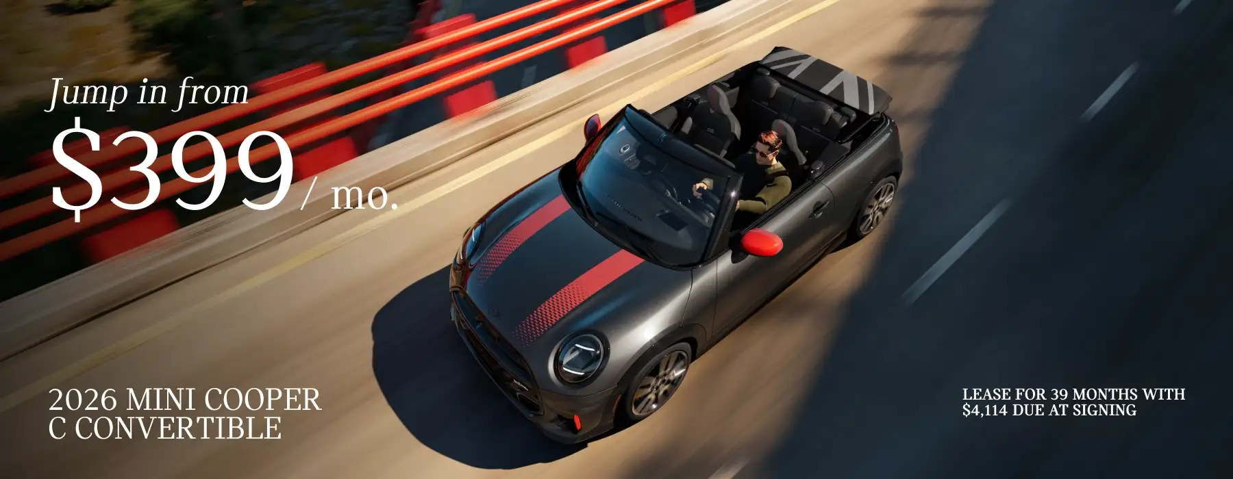 2026 MINI Cooper C Convertible driving along a road with the top down. Lease offer starting at $399 per month for 39 months, with $4,114 due at signing.