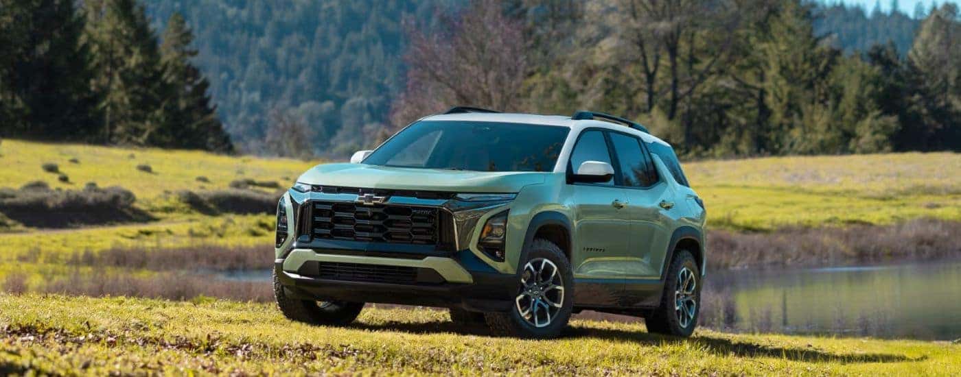A green 2026 Chevy Equinox parked on a field by a pond.