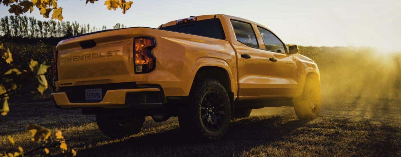 A sunrise orange 2026 Chevy Colorado WT parked in a field rear-facing.