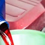 close up of technician pouring transmission fluid into funnel