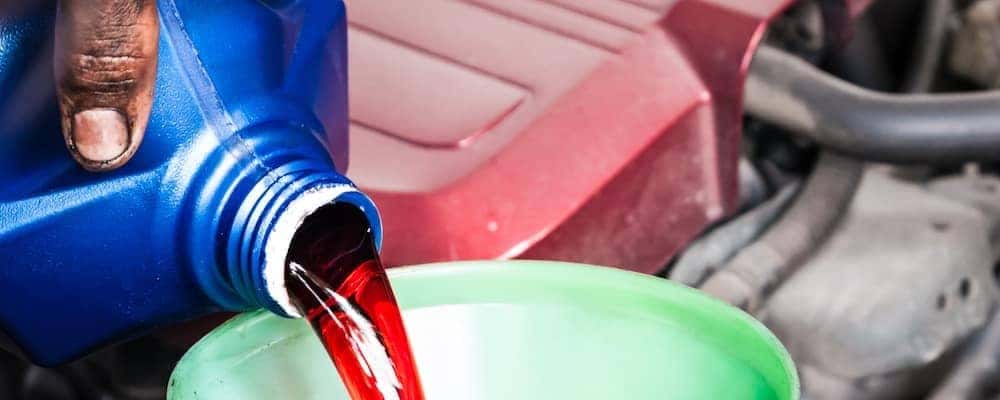 close up of technician pouring transmission fluid into funnel