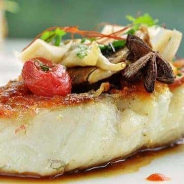 grilled fish on a plate with decorative sauce
