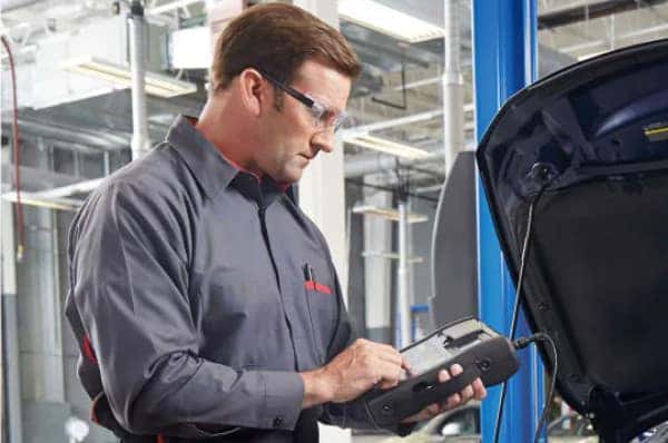 Nissan Service Center employee stands with arms crossed.