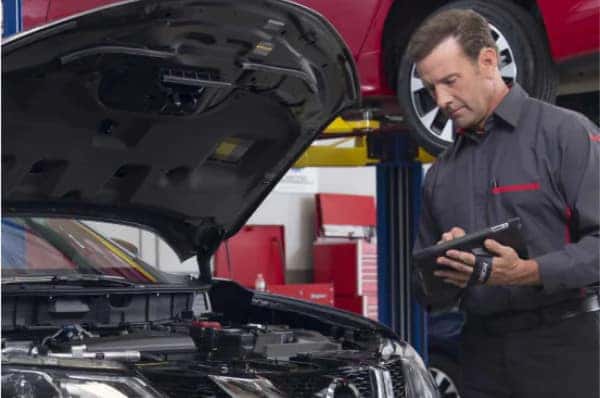 Nissan Service Center employee stands with arms crossed.
