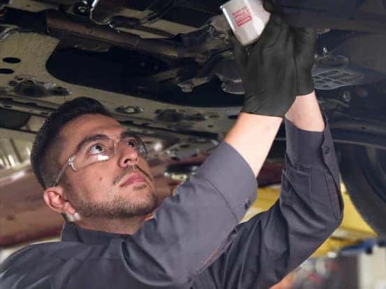 Nissan Service Center employee standing under a lifted car.