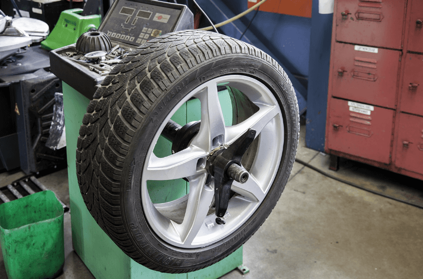 A tire is secured to the side of a mechanic's toolbox in a garage