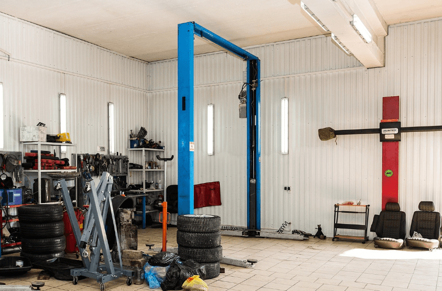 An empty mechanic's rack next to shelves crowded with tools and car parts