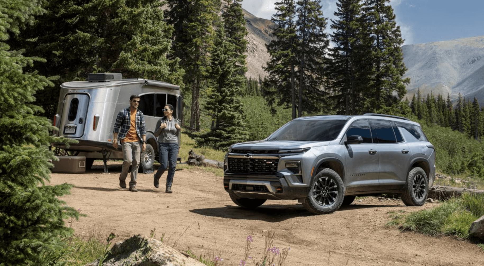 2025 Chevy Traverse parked in the mountains with a camper next to it