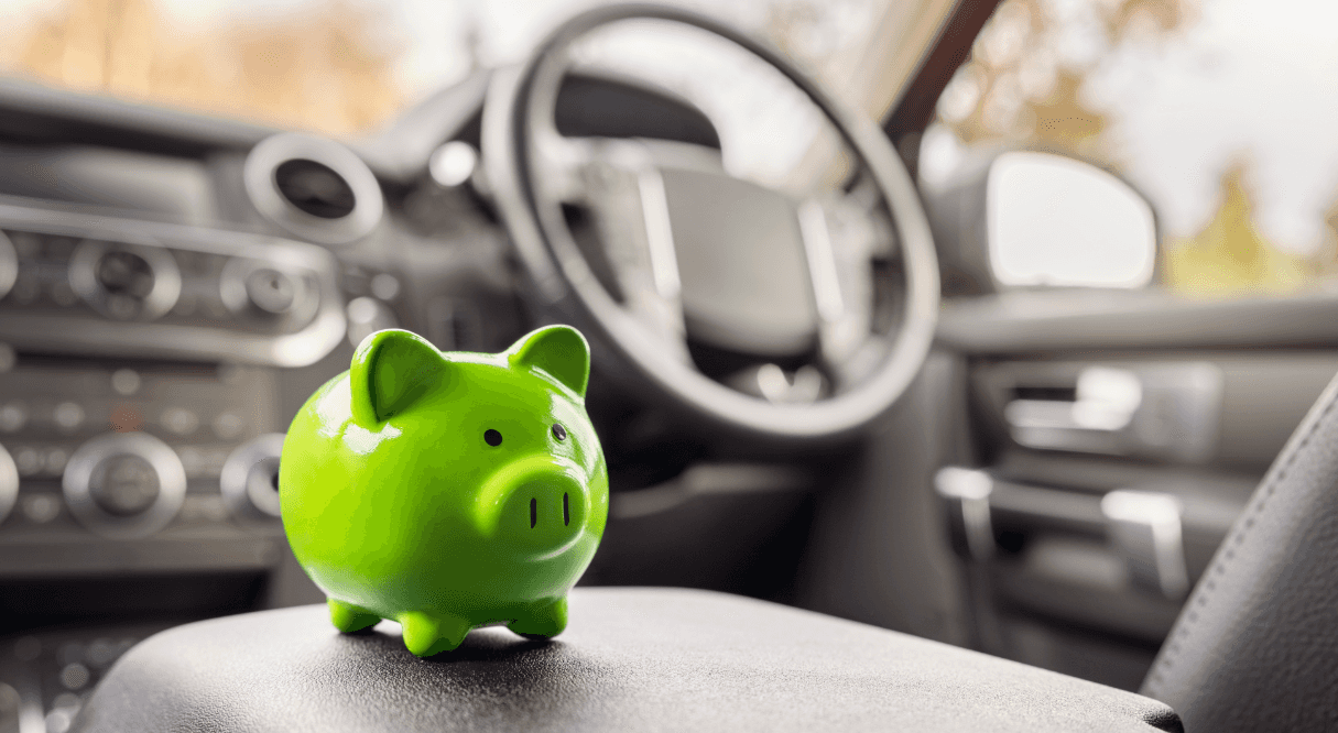 Green piggybank on top of the front console in a car