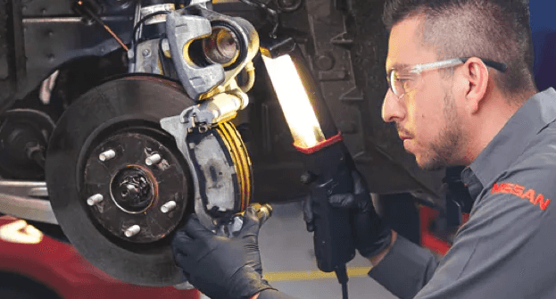 A certified Nissan technician examining a vehicle brake (1)