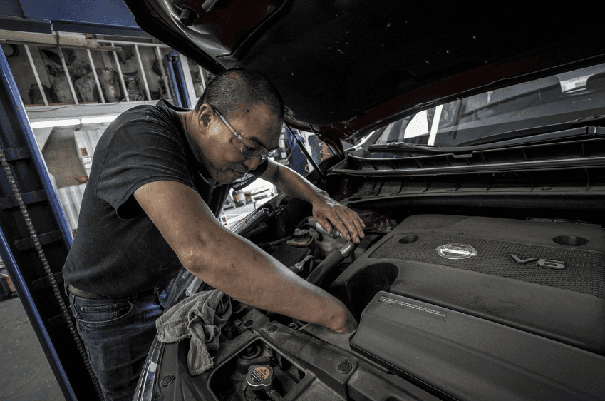 A man works under the hood of a Nissan vehicle