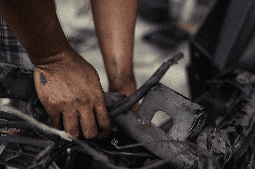 A pair of dirty hands repairing an engine