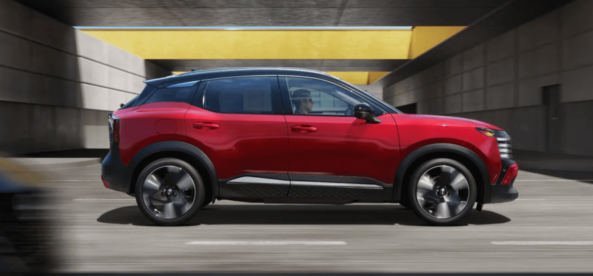 side view of a new Nissan kicks driving on the street
