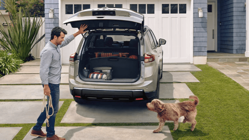 A man letting his dog into a Nissan Rogue