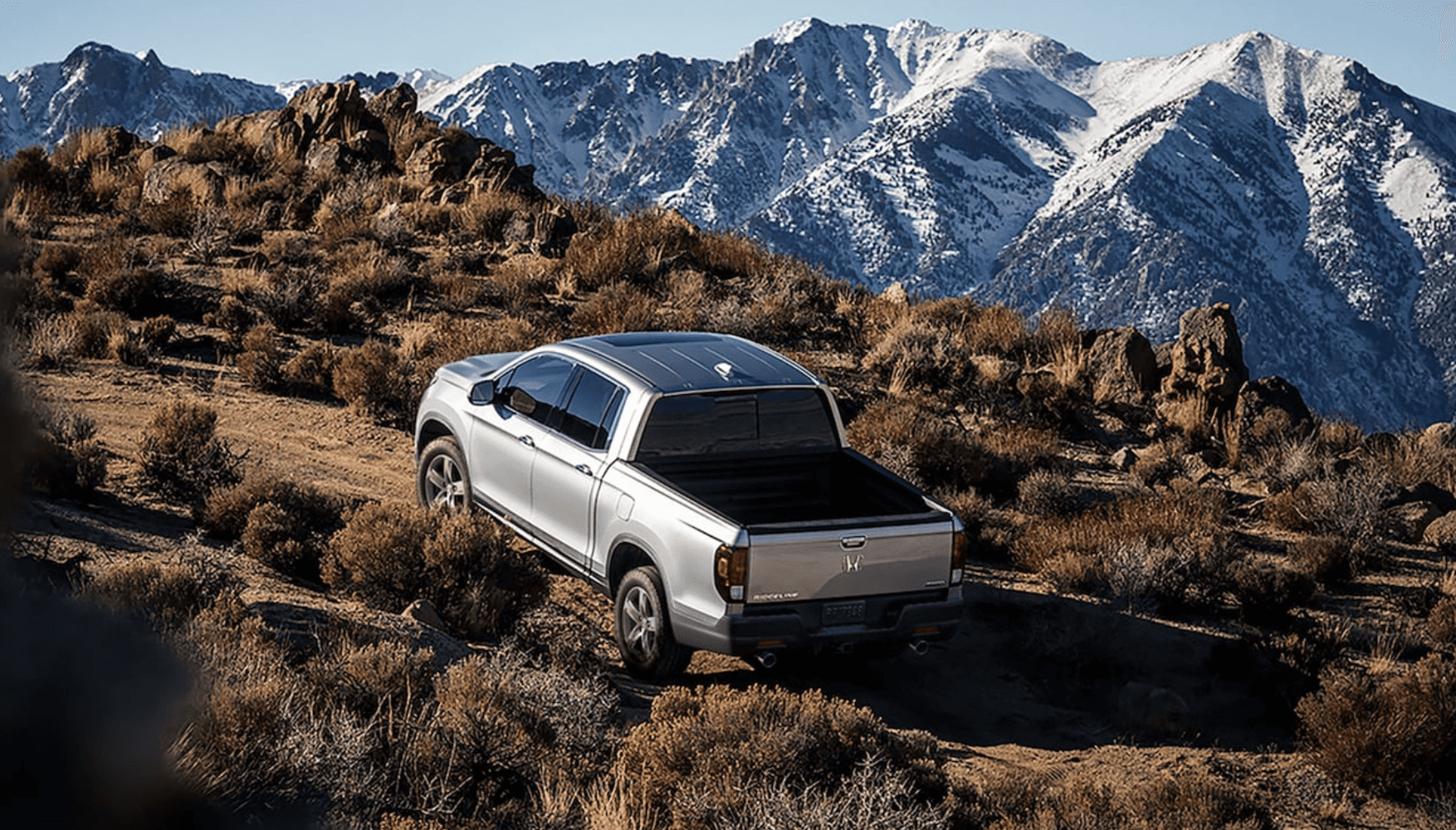 2024 Silver Honda Ridgeline driving up a mountain