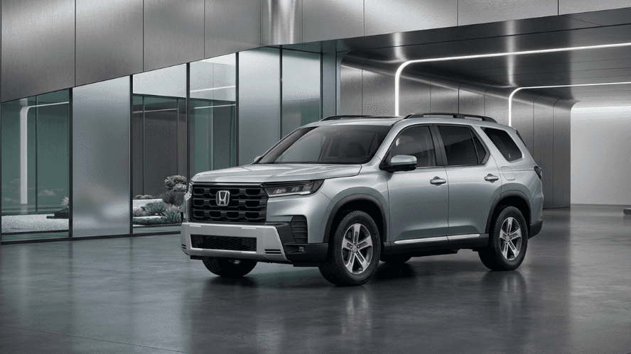 Silver Honda Pilot Touring SUV parked in a modern, architecturally clean showroom with polished concrete floors and glass panels.