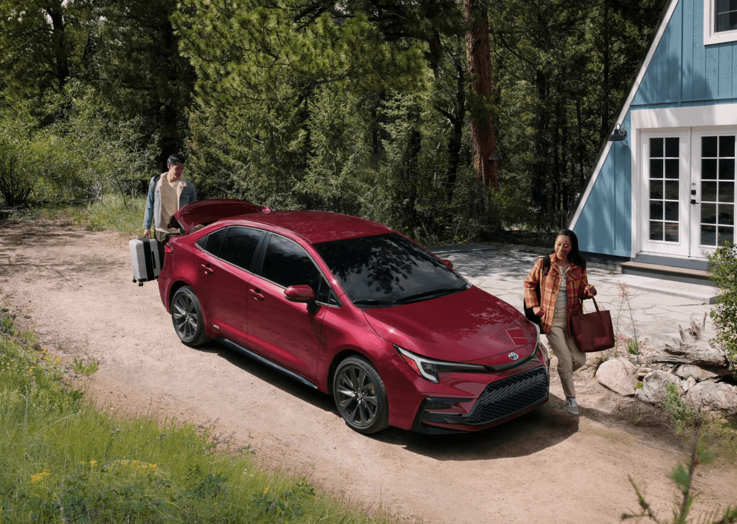 People unloading their luggage from a 2025 Toyota Corolla parked in front of a travel lodge
