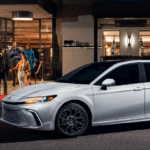 A 2025 Toyota Camry XSE parked on a valet stand in front of a busy restaurant at night