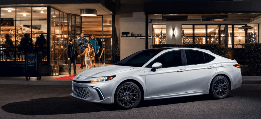 A 2025 Toyota Camry XSE parked on a valet stand in front of a busy restaurant at night
