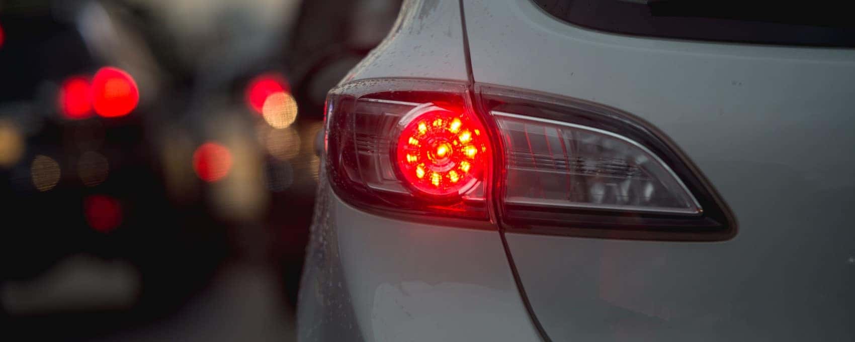 Brake light on white car with traffic in background