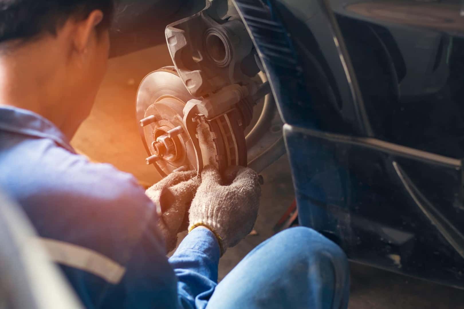 Service technician replacing brake pads on vehicle