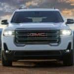 A white 2020 GMC Acadia AT4 is parked in front of mountains.