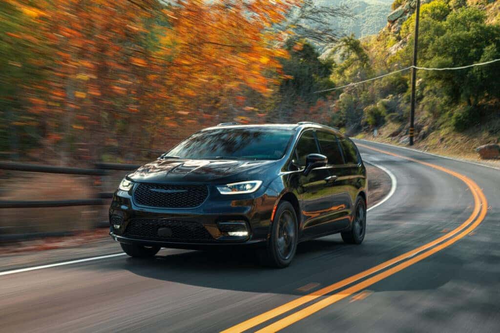A black 2025 Chrysler Pacifica driving on a curvy road.