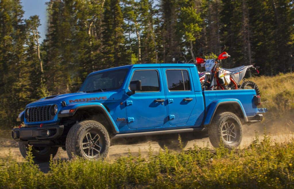 A blue 2025 Jeep Gladiator in the forest.