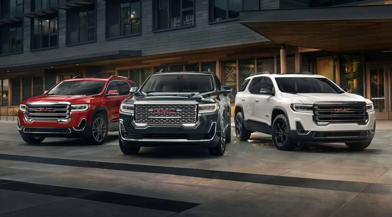 Three GMC vehicles parked in front of a building