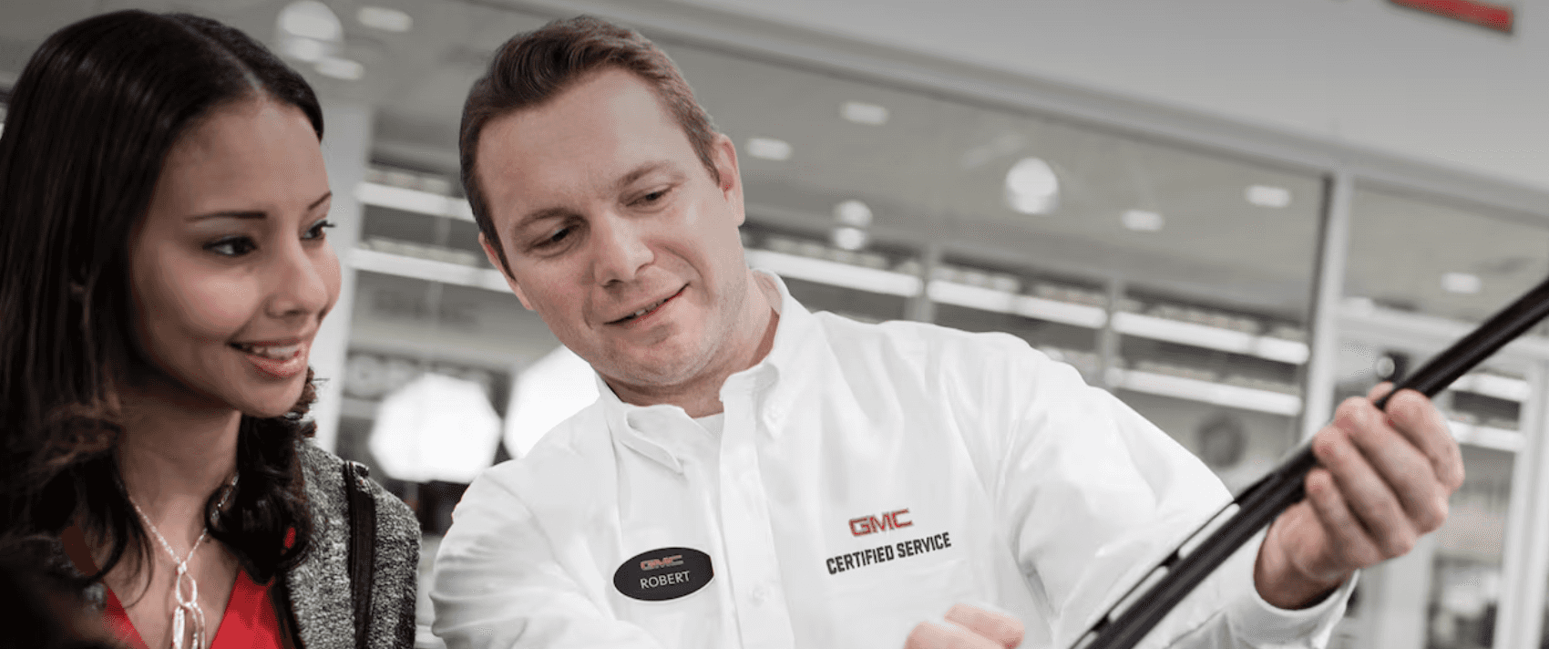 GMC technician showing a new windshield wiper blade to a customer