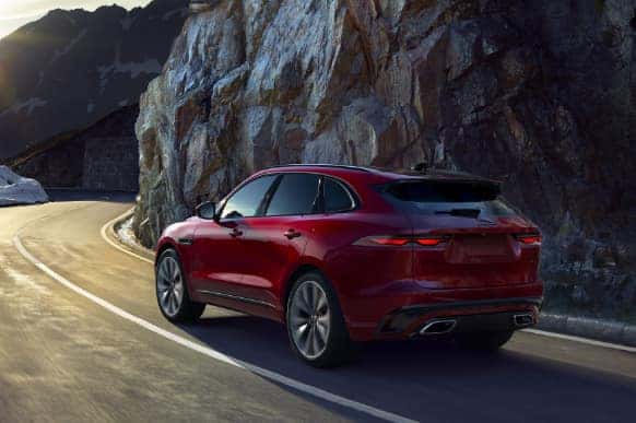 Red Jaguar F-PACE driving through mountains.