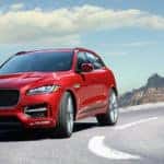 red 2019 jaguar f-pace driving on highway with mountains in background
