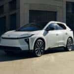 White Toyota bZ parked in the shadow of a building.