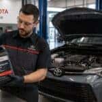 Technician holding coolant in front of Toyota car
