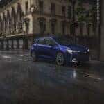 dark blue 2027 Toyota Corolla Hatchback quartering toward, driving on rainy road