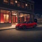 Red Camry at night in front of a building