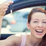 Women leaning out car window smiling and holding car keys
