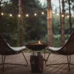 Back porch with two cozy chairs on it and fireplace. Blankets and coffee cups waiting for someone to enjoy in them.