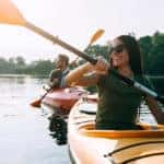 Beautiful young couple kayaking on lake together and smiling