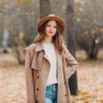 Woman in an autumn park in a wool coat and wide brim hat