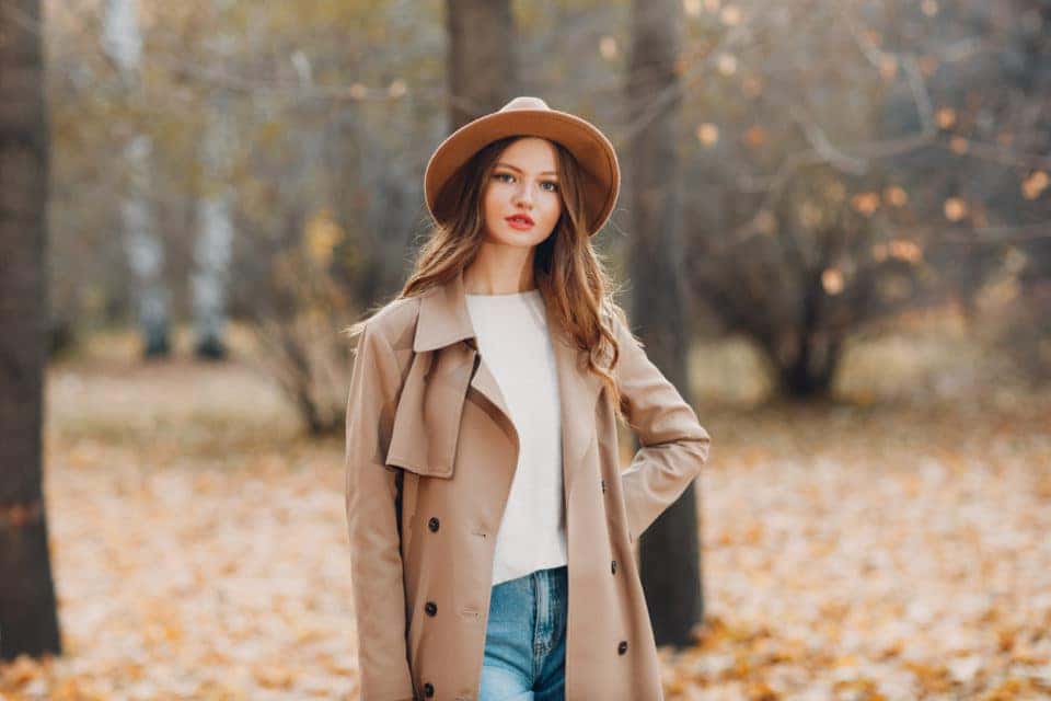 Woman in an autumn park in a wool coat and wide brim hat