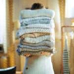 A Woman storing a pile of winter sweaters
