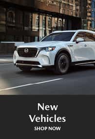 New white Mazda SUV parked on a city street.