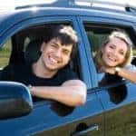 Happy young couple driving in blue car