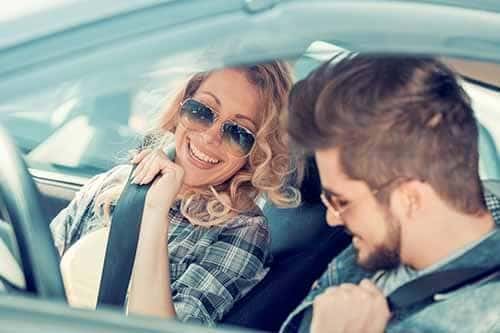 Two people driving in convertible smiling