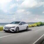 Mercedes-Benz EQE driving down a highway by the ocean